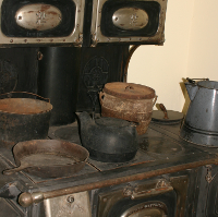 Old-fashioned stove with many pans, pots and kettles on it